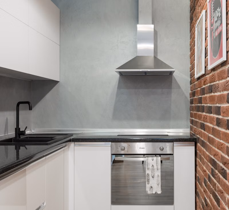 Technician servicing the motor assembly inside a stainless steel range hood